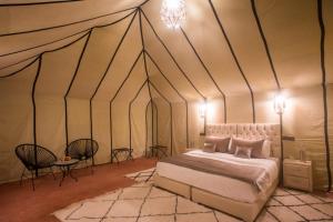 a bedroom with a tent with a bed and a table at Luxury Desert Camp Amanar in Merzouga