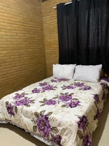 ein Bett mit lila Blumen auf einem Zimmer in der Unterkunft Chalés Bem-me-quer Itaipava in Itaipava