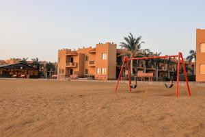 a swing set on a beach with buildings in the background at Alahlam Resort Yanbu in Yanbu