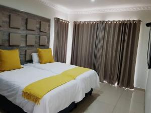 2 Betten mit gelben Kissen im Schlafzimmer in der Unterkunft 8sIndoor indoor pool4 bedroom villaGreat view and backup power in Clarens