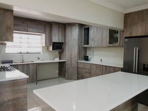 cocina con armarios de madera y encimera blanca en 8sIndoor indoor pool4 bedroom villaGreat view and backup power, en Clarens