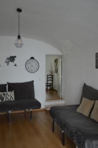 ein Wohnzimmer mit einer Couch und einer Uhr an der Wand in der Unterkunft Évora Romana Alojamentos T1 Templo Diana in Évora