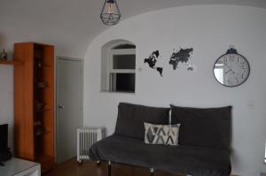 ein Zimmer mit einem Sofa und einer Uhr an der Wand in der Unterkunft Évora Romana Alojamentos T1 Templo Diana in Évora
