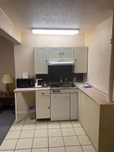 a small kitchen with white cabinets and a sink at Chinook Motel in Lethbridge