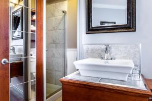 a bathroom with a white sink and a shower at Hotel Maison du Général in Quebec City