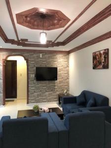 阿可賀巴的住宿－Beyoot Alsharq Furnished Units，客厅配有蓝色的沙发和平面电视。