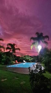 a swimming pool at night with a purple sky at Pousada Areias do Embaú in Guarda do Embaú