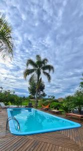 瓜德丁堡的住宿－Pousada Areias do Embaú，棕榈树木甲板上的蓝色游泳池