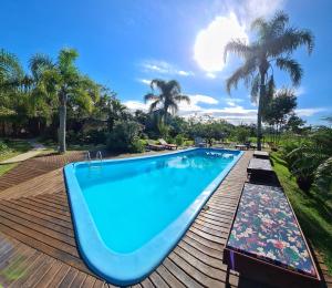 a swimming pool on a wooden deck with palm trees at Pousada Areias do Embaú in Guarda do Embaú