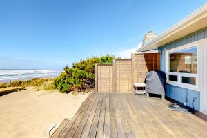 a house with a wooden deck next to the beach at Rockin' Away Beach House in Rockaway Beach