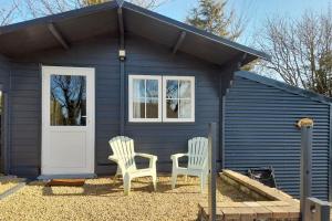 two chairs in front of a blue tiny house at Delightful Studio Log Cabin , with Sauna in Coolnacon