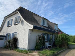 une maison blanche avec des fenêtres bleues et un banc dans l'établissement Achtern Meerdiek, à Nordstrand