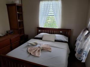 a bed with two towels on it with a window at The Sands Inn-Upper Floor with pool in Caye Caulker