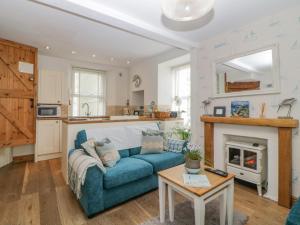 a living room with a blue couch and a fireplace at Curlews Cottage in Looe