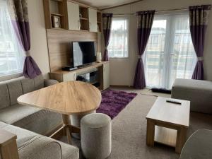 a living room with a couch and a table at 'Oakley' Boat of Garten Holiday Park in Boat of Garten