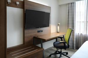a hotel room with a desk and a television on a wall at Holiday Inn Express Toronto Downtown, an IHG Hotel in Toronto