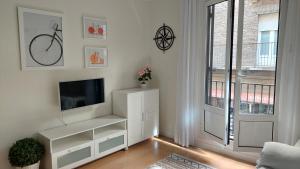 a white living room with a tv and a window at Ibarrenea Apartamento in Pamplona