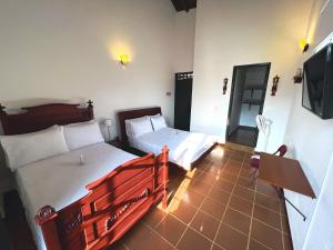 a bedroom with two beds and a flat screen tv at El Portón de Enriqueta in Guaduas