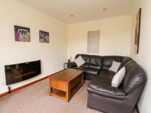 a living room with a leather couch and a coffee table at Glen Dessary in Banavie