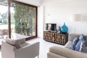 a living room with two chairs and a television at Beach House Pedras D'el Rei in Santa Luzia