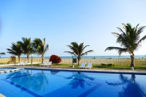 a swimming pool with palm trees and the ocean at Ecusuites Playas Suite 3 Preference Balcón & Jacuzzi Vista al Mar in Playas