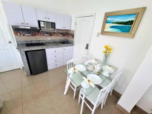 a kitchen with a glass table and white chairs at Ecusuites Playas Suite 3 Preference Balcón & Jacuzzi Vista al Mar in Playas