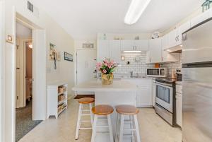 a kitchen with white cabinets and a counter with stools at Plantation East in Gulf Shores