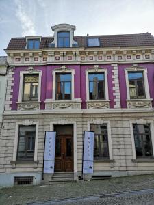 - un bâtiment violet avec des fenêtres et des portes dans une rue dans l'établissement L'ARTiste, à Lessines