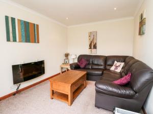 a living room with a leather couch and a coffee table at Glen Pean in Banavie