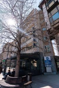 dos personas sentadas en un banco junto a un árbol en Best Western Hotel Turist - Superior, en Skopje