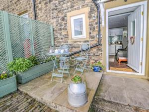a patio with a table and chairs in front of a building at The Mistle Carr Farm in Ripponden