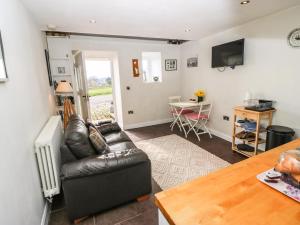 a living room with a leather couch and a table at The Mistle Carr Farm in Ripponden