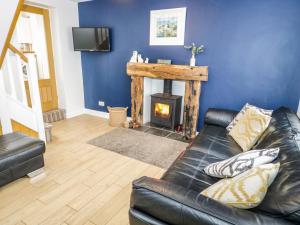 a living room with a leather couch and a fireplace at Bodfan Peniel in Llanerchymedd