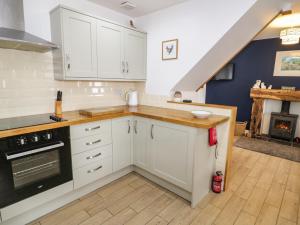 a kitchen with white cabinets and a stove top oven at Bodfan Peniel in Llanerchymedd