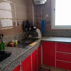 uma cozinha com armários vermelhos e um lavatório em salwa em Ifrane