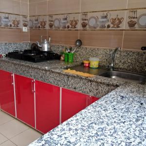 a kitchen with red cabinets and a sink at salwa in Ifrane