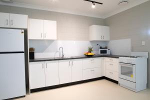 a kitchen with white cabinets and a white refrigerator at Apartments at Mission Beach in Mission Beach