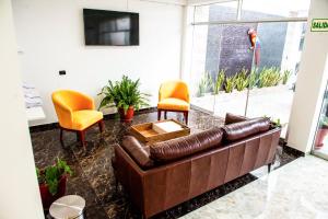 a living room with a brown couch and two chairs at Hotel Boutique Papagayo in Tarapoto