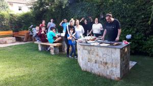 un grupo de personas parados alrededor de una parrilla en un patio en Chale de Madeira - Lareira e Fogueira---lindo gramado com mesa para café da manhã, churrasqueira e fogueira en Campos do Jordão