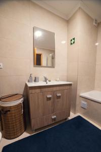 a bathroom with a sink and a mirror and a tub at Casa Maria do Ilhéu in Vila Franca do Campo