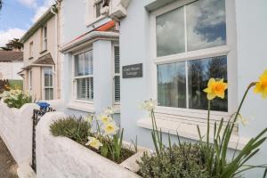 a white house with flowers in front of it at Cool Stone Cottage in Instow