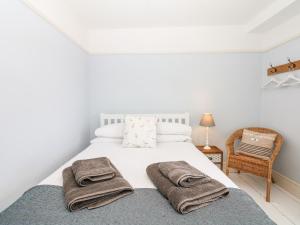 a bedroom with a white bed with towels on it at Cool Stone Cottage in Instow