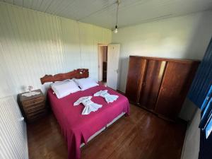 a bedroom with a bed with pink sheets and white towels at Casa Foresti in Bento Gonçalves