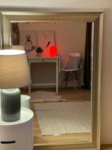 um espelho num quarto com uma mesa e uma cadeira em Schickes Apartment mit Balkon in Düsseldorf em Düsseldorf