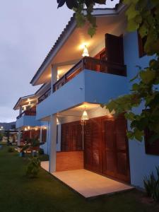 Cette maison blanche dispose de portes en bois et d'une terrasse couverte. dans l'établissement Condominio Vila Lila, à Garopaba