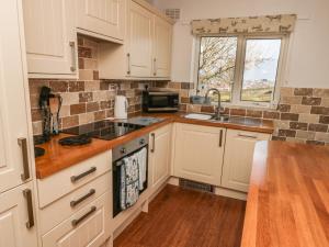 a kitchen with white cabinets and a sink and a window at Crud Yr Awel in Amlwch