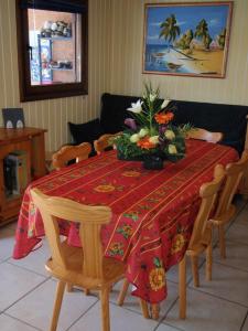 uma mesa com uma toalha de mesa vermelha com flores em Maison avec piscine chauffée de Pâques à la toussaint accès animation & parc aquatique en supplément de juin à fin septembre em Portiragnes
