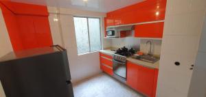 una pequeña cocina con armarios rojos y fregadero en LISBOA Hermoso departamento para 6 personas en cdmx, en Ciudad de México