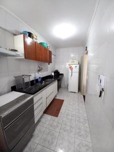 uma pequena cozinha com um frigorífico e um lavatório em Apartamento 500M da Praia Enseada, Guarujá no Guarujá