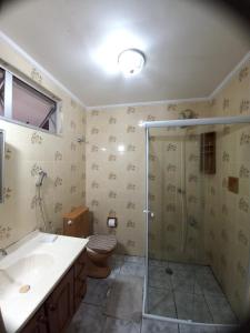 uma casa de banho com um chuveiro, um WC e um lavatório. em Apartamento 500M da Praia Enseada, Guarujá no Guarujá